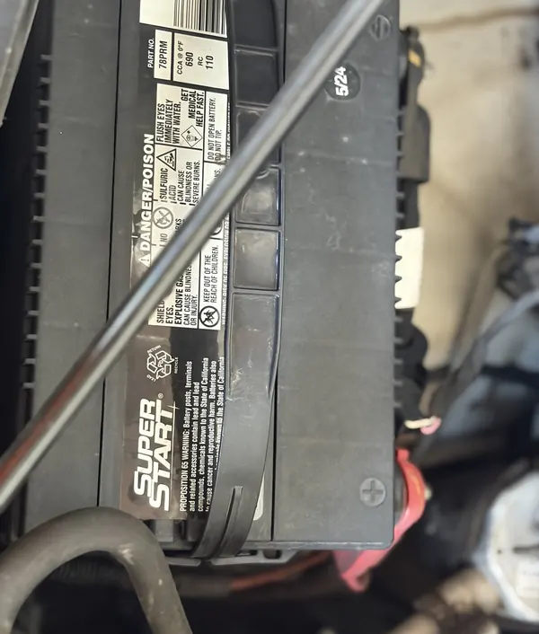 A battery under the hood, held in its tray