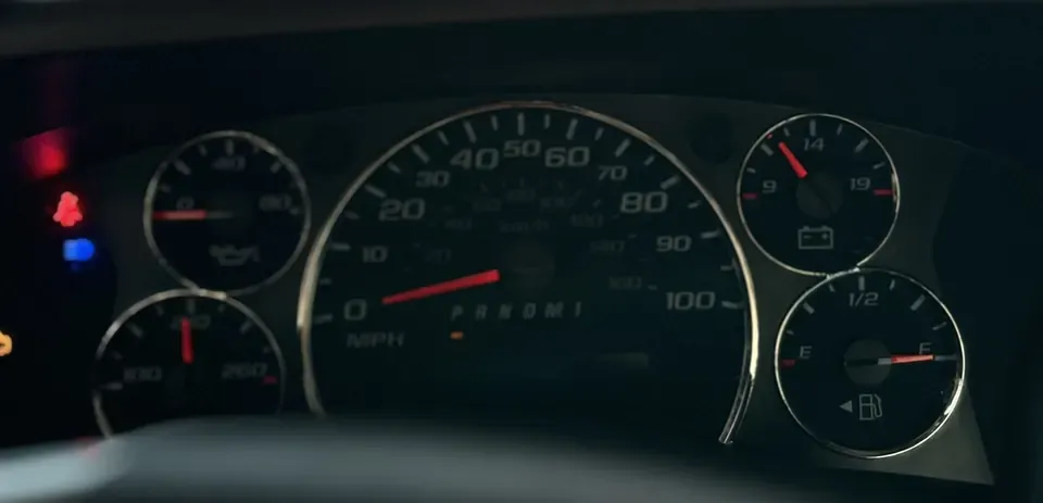 The instrument cluster with the blue high-beam light on at the left