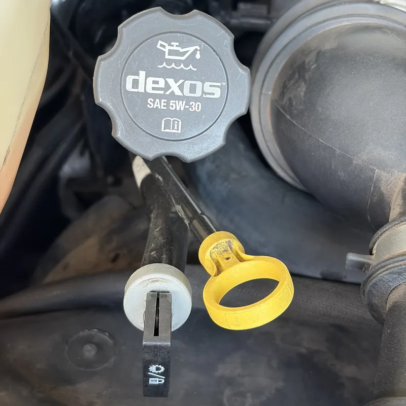Engine oil fill cap marked SAE 5W-30, with the yellow oil dipstick handle below it