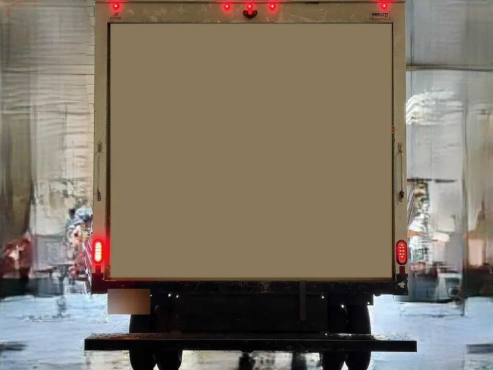 Back of the box truck with its red lights on; the company details on the door are covered