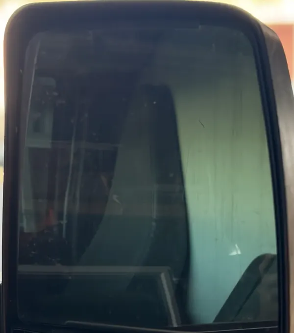 A side mirror with dust and water spots on the glass