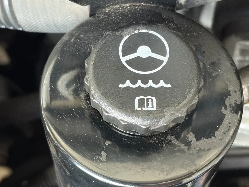 Power steering reservoir cap with a steering wheel symbol