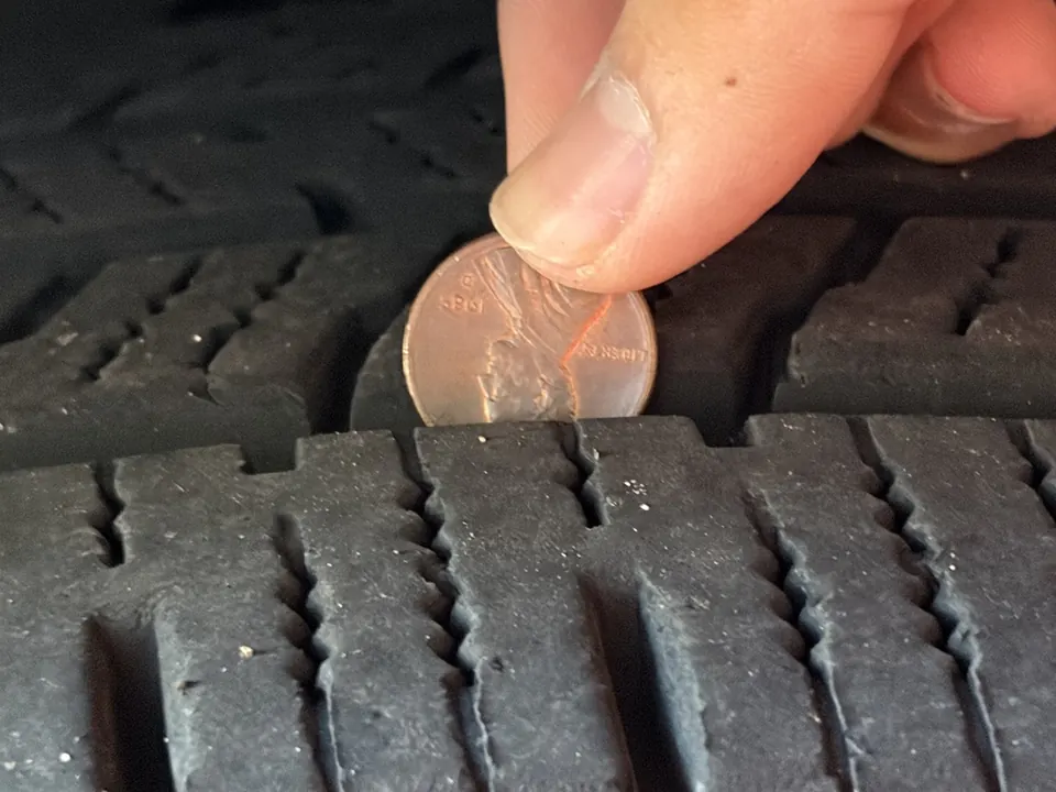 A penny pushed head first into a tire groove