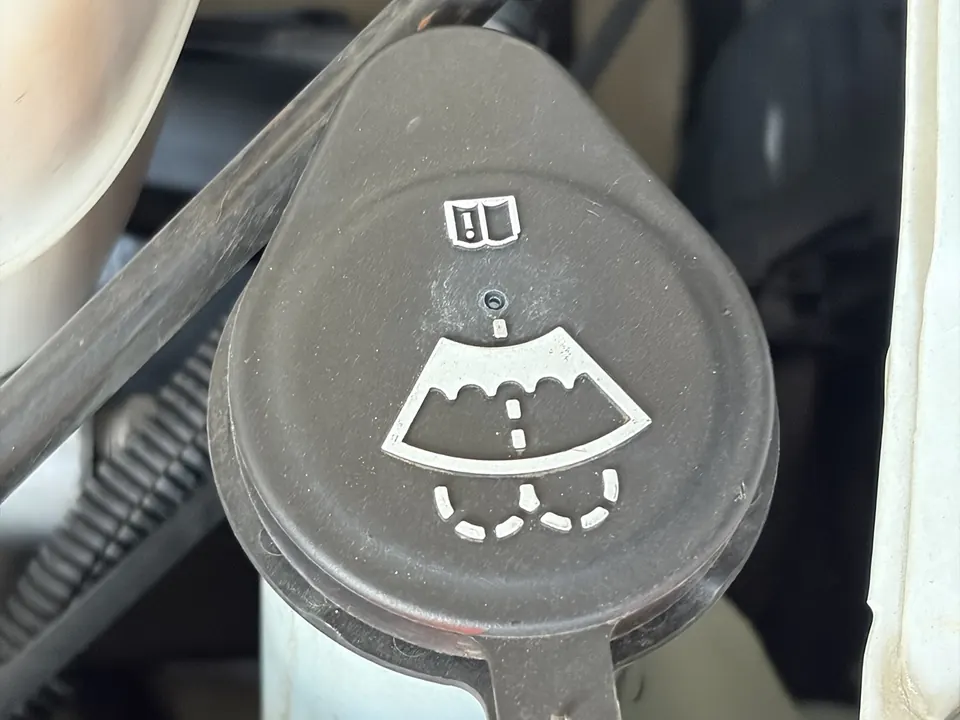 Washer fluid tank cap with a windshield and spray symbol